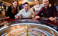 Excited group of friends playing roulette in casino